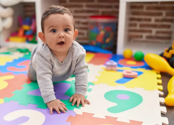 Un bébé à quatre pattes sur un tapis de jeu coloré.