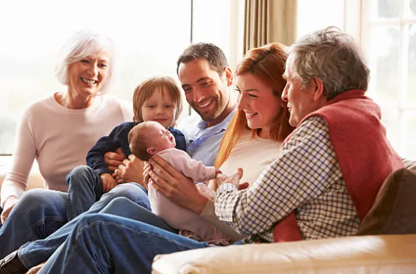 Trois générations réunies sur un canapé autour d'un nouveau-né.