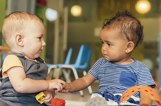 Deux bébés se tiennent la main en jouant.